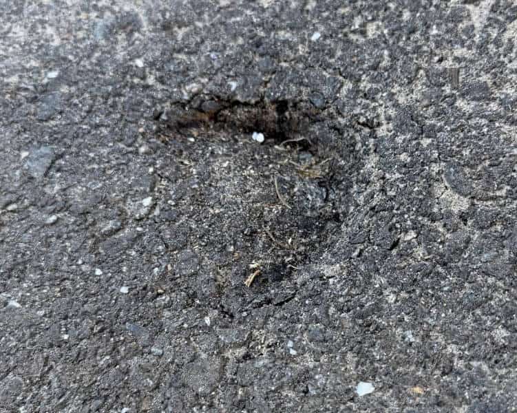 Reference photo showing a small round depression in an asphalt surface
